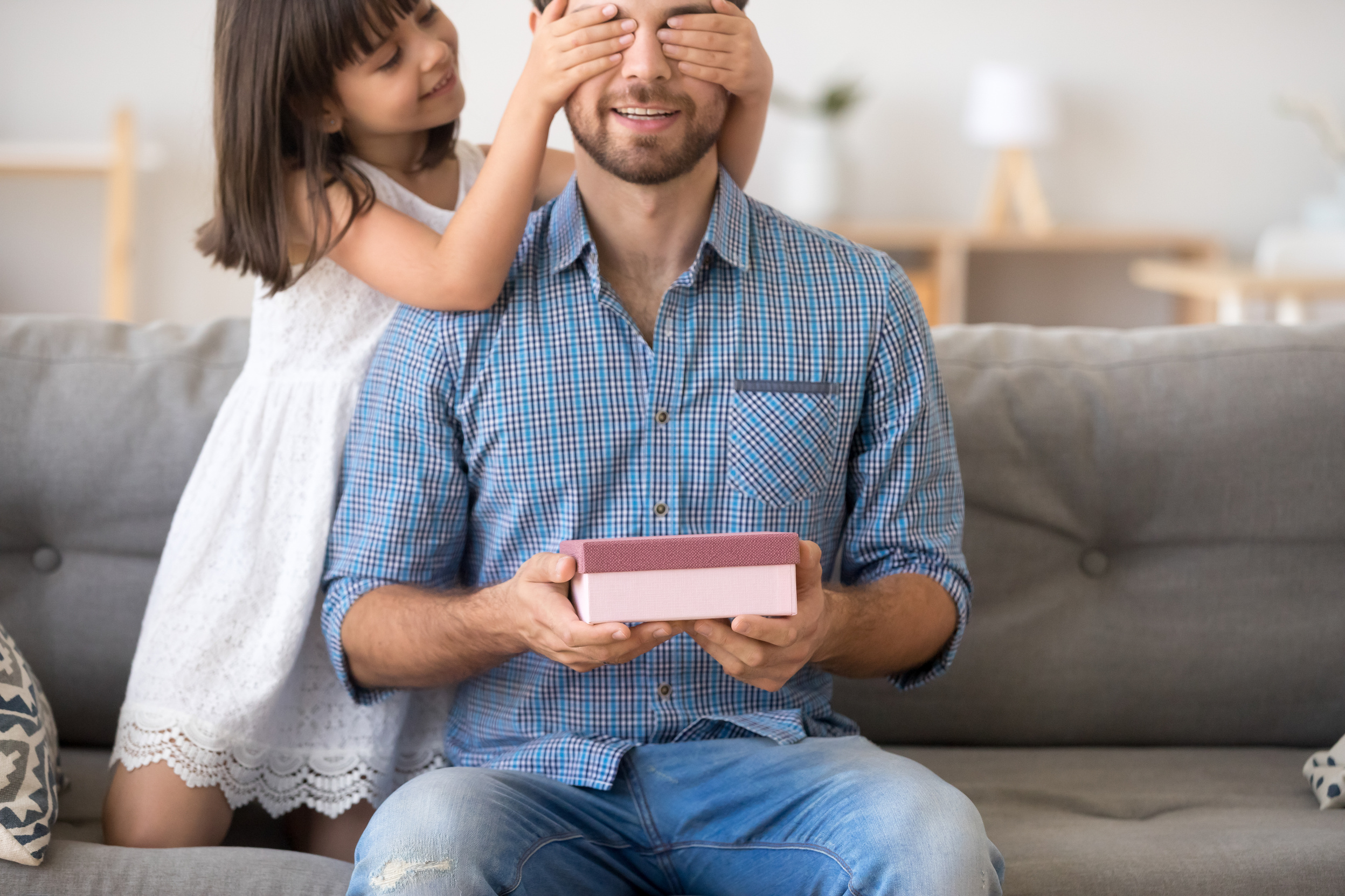 Little daughter presenting gift box making surprise for happy dad